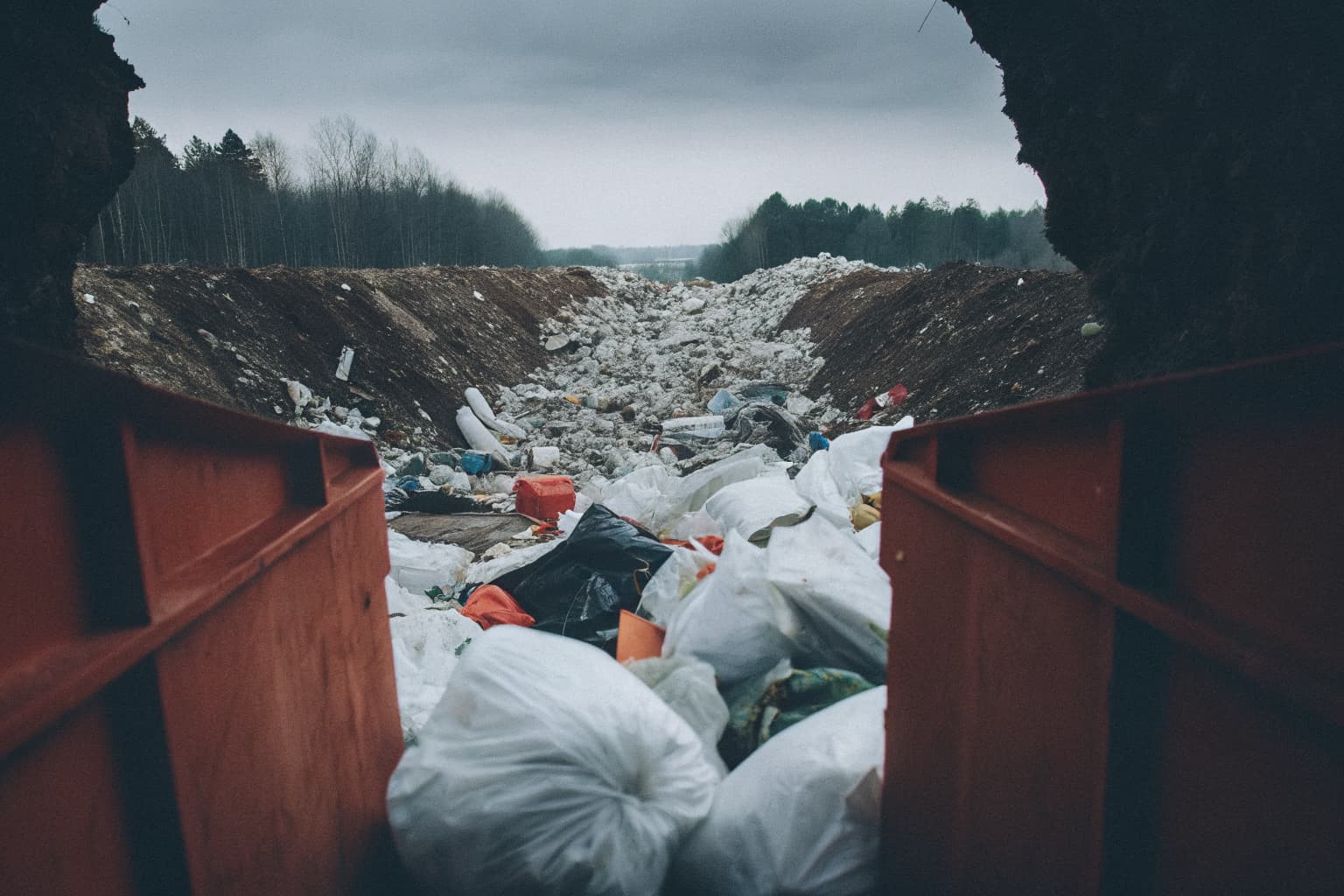 A landfill mound of discarded plastic waste stretching to the horizon