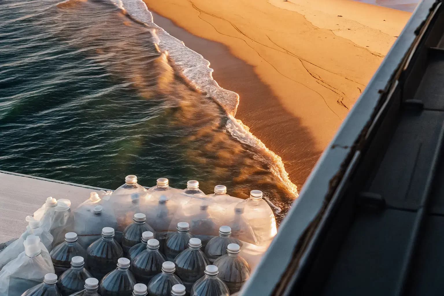 Plastic bottles washing onto a pristine ocean coastline at golden hour